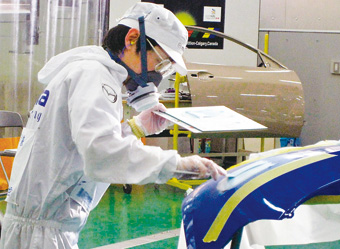 Mazda employee Takeshi Tsutsumi, shown here painting a vehicle at a Mazda headquarters training facility